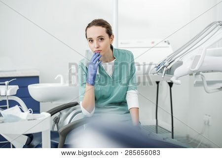 Selective Socus Of Pensive Female Dentist Sitting In Dental Clinic