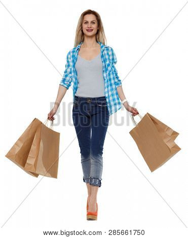 Front view of a woman walking with shopping bags. beautiful girl in motion.  Frontside view of person.   Isolated over white background. Slender blonde in heels goes swinging shopping bags.
