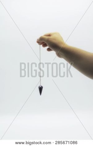 Pendulum Dowsing On An Isolated White Background With An Amethyst Crystal.