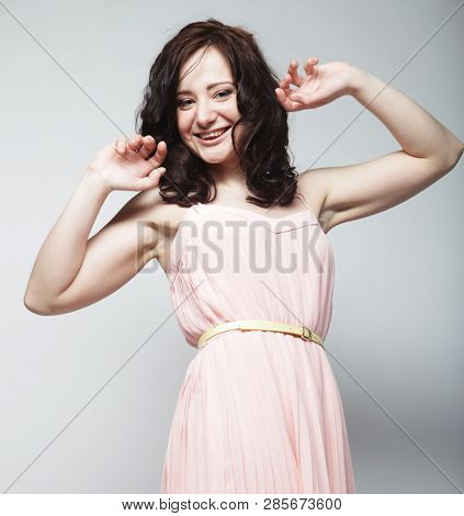 young brunetee  woman wearing pink dress and posing over white background