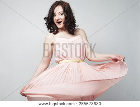 young brunetee  woman wearing pink dress and posing over white background
