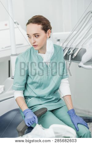 Selective Socus Of Sad Female Dentist Sitting In Dental Clinic