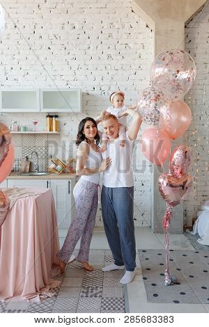 Happy Family: Mother, Father And Little Daughter  Celebrating First Birthday Holiday Party On Pink.
