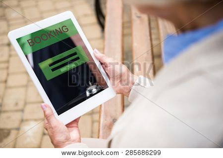 Selective Focus Of Senior Woman Using Digitale Table With Booking On Screen