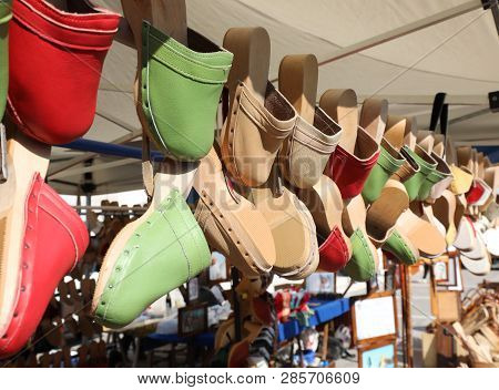 Many Wooden And Leather Clogs Hanging On Sale In The Stall Of Handmade Shoes
