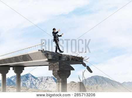 Businessman Walking Blindfolded On Concrete Bridge With Huge Gap As Symbol Of Hidden Threats And Ris