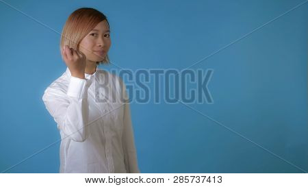 Portrait Young Asian Female Posing Showing Sign Knocking At The Viewer Calling For Attention On Blue