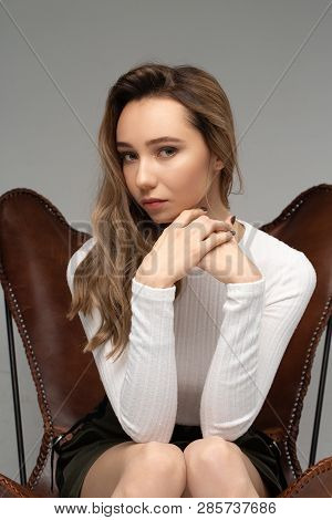 Portrait Of Beautiful Young Model In White T-shit Sitting On Brown Vintage Chair