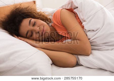 African-american Woman Sleeping Sweetly On Bed And Smiling