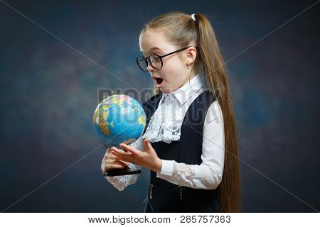 Amazed Little Blond Schoolgirl Look At World Globe. Primary School Student Study Geography. Suprised