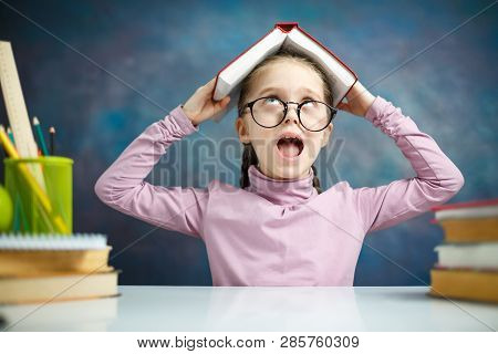 Cute Schoolgirl Shout Cover Head With Open Book. Closeup Portrait Of Elementary School Student Scree