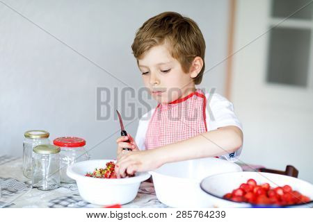 Little Blond Kid Boy Helping And Making Strawberry Jam In Summer. Funny Child Cleaning Berries And P