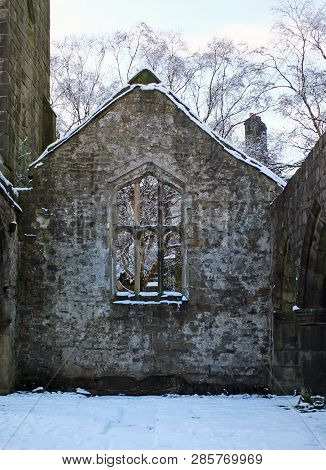 View Through A Window In The Wall Of A Medieval Ruined Church In Heptonstall Yorkshire With Snow Cov
