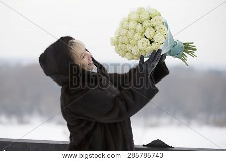 Portrait Of A Happy Woman With A Bouquet Of Roses On A Winter Background