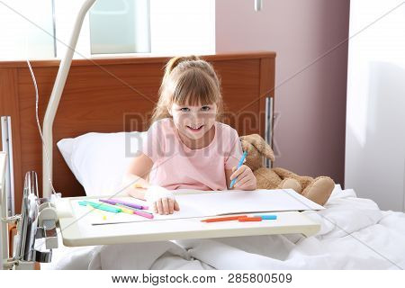 Little Child With Intravenous Drip Drawing In Hospital Bed