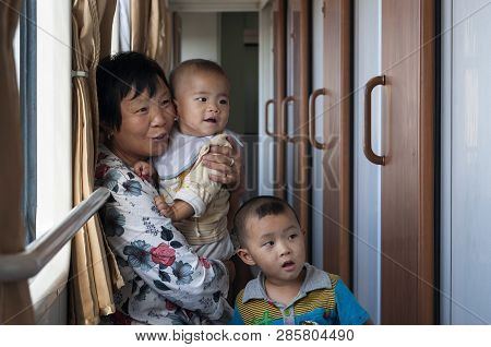 Xinjiang, China - August 11, 2012: Woman With Two Babies Traveling By Train In The Xinjiang Region, 