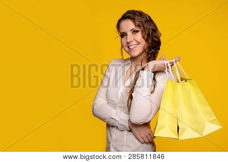 Picture Of Beautiful Smiling Young Woman In White Blouse Holding Cruft Bags After Shopping