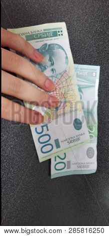 A Girl Puts Fingers On Paper Serbian Money On Black Table