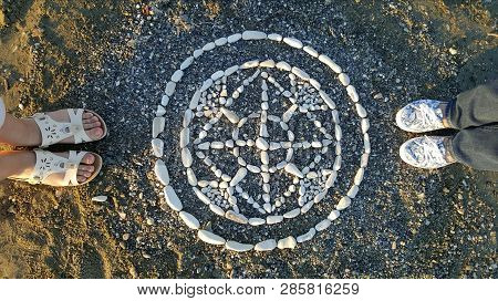 Four Legs Standing Near Oriental Round Mandala Made Of Stones At Sea Shore