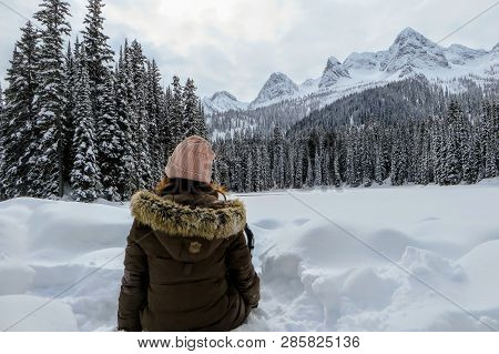 A Young Woman Admiring The Snowy Views Of Island Lake In Fernie, British Columbia, Canada.  The Maje