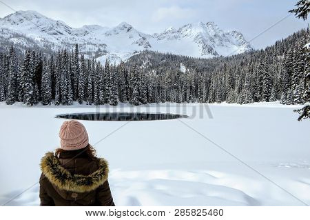 A Young Woman Admiring The Snowy Views Of Island Lake In Fernie, British Columbia, Canada.  The Maje