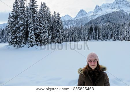 A Young Woman Posing With The Forests Of Island Lake In Fernie, British Columbia, Canada Behind.  Th
