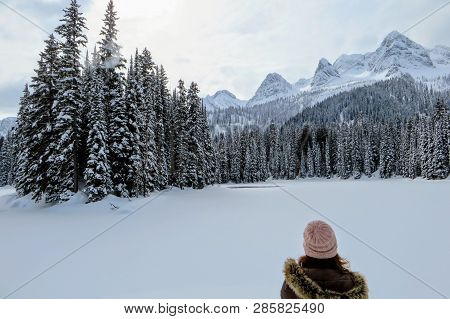 A Young Woman Admiring The Snowy Views Of Island Lake In Fernie, British Columbia, Canada.  The Maje