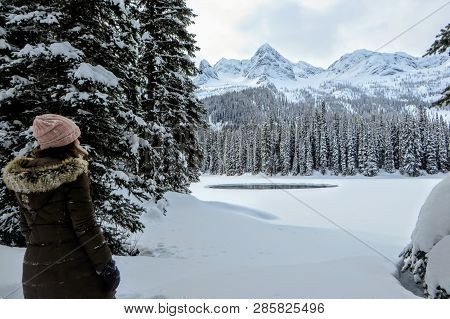 A Young Woman Admiring The Snowy Views Of Island Lake In Fernie, British Columbia, Canada.  The Maje
