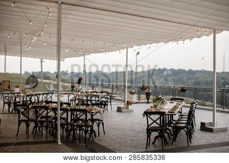 Big Restauraunt Terrace With A Lot Of Served Tables. A Hill With A Forest On The Background.