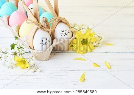 Easter Colored Eggs With Painted Faces In Paper Tray With Decorationd On White Background