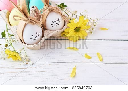 Easter Colored Eggs With Painted Faces In Paper Tray With Decorationd On White Background
