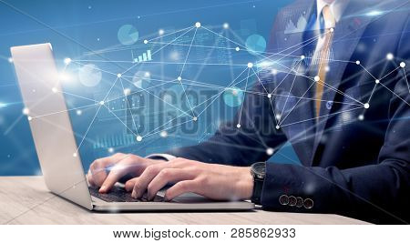 Businessman typing on laptop with linked reports charts grapghs around
