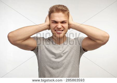 Photo Of Desperate Annoyed Bearded Man Keeps Hands On Head, Holds Palms On Ears, Ignores Annoying So
