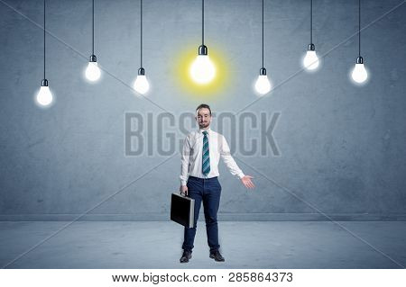 Handsome businessman in an empty space with bulbs above and uninspired face