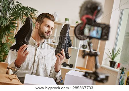 Popular Fashion Blogger. Young Male Fashion Blogger Holding Stylish Sneakers While Making New Conten