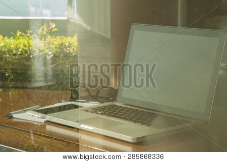 Reflections Of Laptops, Glasses, Mobile Phones, Notebooks And Pens On Wooden Tables For Work