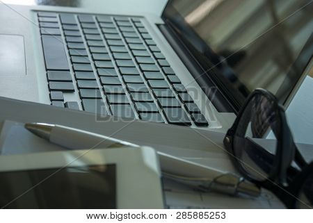 Work Area With A Laptop And Tablet To Work Documents, Notebooks, Pens And Glasses