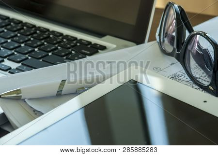 Top View Of The Table With Laptops And Tablets, Including Glasses, Notebooks, Pens And Work Document