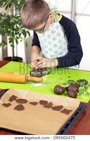 Boy Squeezes The Shapes From The Molds On The Rolled Brown Dough. Pressed Shapes Are Next To Prepare