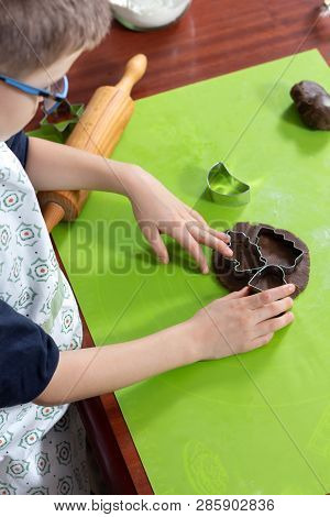 Boy Squeezes The Shapes From The Molds On The Rolled Brown Dough. Pressed Shapes Are Next To Prepare