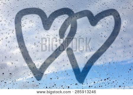 Picture Of Two Hearts On A Misted Glass. Glass Window With Raindrops Against The Blue Sky. Concept O