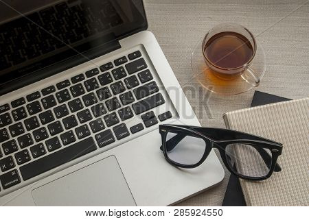 Work Area With A Laptop With Notebooks, Glasses And 1 Glass Of Tea