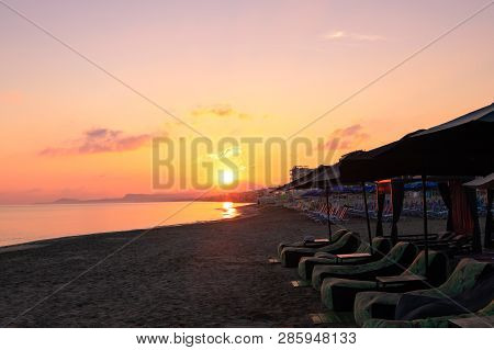 Morning On The Beach Near The Sea. Sun Chairs On Sandy Beach At Sunrise, Crete, Retimno. Beautifull 