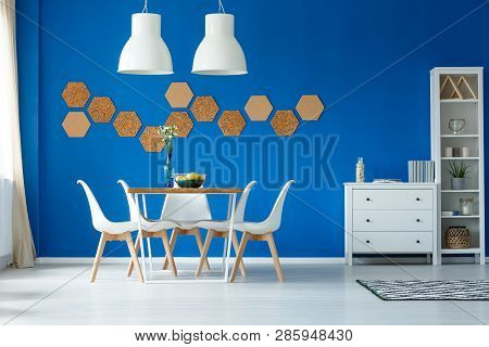 Big White Metal Lamps Above Wooden Table With White Chairs In Lovely Dining Room Interior With Blue