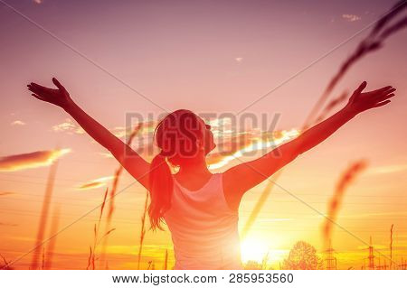 Free And Happy Woman Raises Arms Against The Sunset Sky. Harmony And Balance