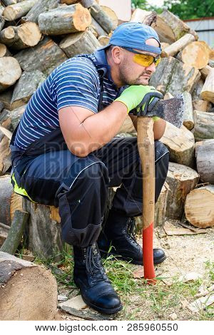 Muscular Young Man Chopping Logs. Heavy Physical Labor.