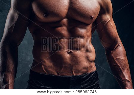 Naked Ahletic Man With Muscular Body. Close-up Image Of Torso With Dark Wall Background