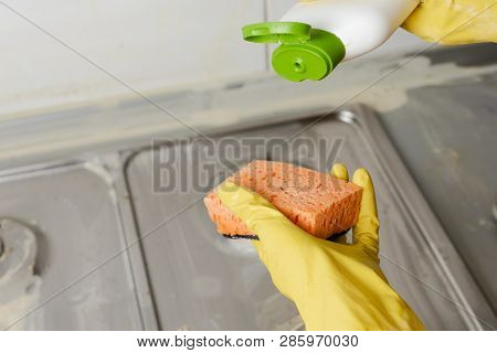 Close-up Of Hand Applying Liquid Soap From Cleanser Bottle To Sponge At Home. Extruding Detergent On