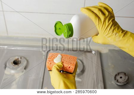 Two Hands Applying Liquid Soap From Cleanser Bottle To Orange Sponge. Extruding Detergent Onto Spong