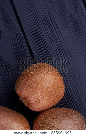 Ripe Brown Kiwi On Dark Wood. Fresh Organic Kiwi And Copy Space On Top, Vertical Image.